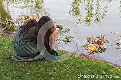 Girl takes pictures of a wreath of flowers in the lake, performing the traditional rite of the holiday of Ivan Kupala Editorial Stock Photo