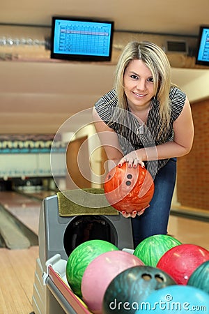 Girl takes two hands ball for playing bowling Stock Photo