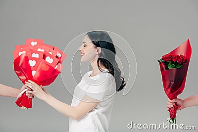 Girl taking bouquet of red paper cut cards near male hand with bouquet of roses isolated on grey Stock Photo