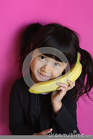 Girl talking on a Banana Stock Photo