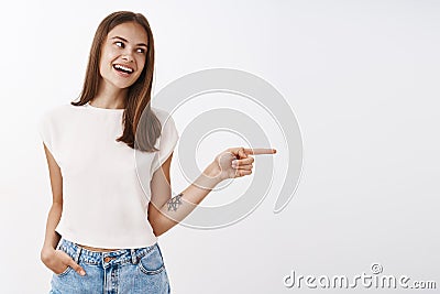 Girl talking to friend pointing right to indicate at person. Charming carefree and confident young stylish female with Stock Photo