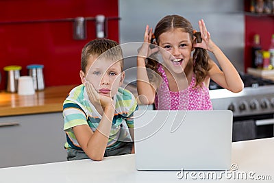 Girl teasing her brother in kitchen Stock Photo