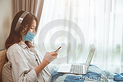 Girl teen covid self quarantine lockdown stay at home enjoy with smartphone internet laptop listening the music Stock Photo