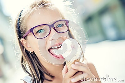 Girl. Teen. Pre teen. Girl with ice cream. Girl with glasses. Girl with teeth braces. Young cute caucasian blond girl wearing Stock Photo