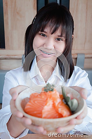 A girl teenage shows a salmon don in a Japanese restaurant Stock Photo