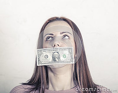 A girl, a teenager, expressive eyes look straight. The mouth is sealed with a cash bill. Long tangled hair, European type. Fee for Stock Photo