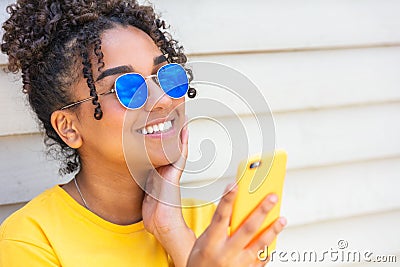 Girl teenager teen female young African American woman wearing sunglasses using cell phone Stock Photo