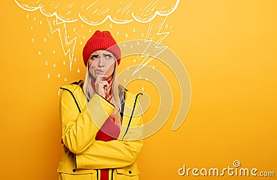 Girl thinks about negative things. Cloud, rain and lightning above her. Confused and pensive expression. Yellow Stock Photo