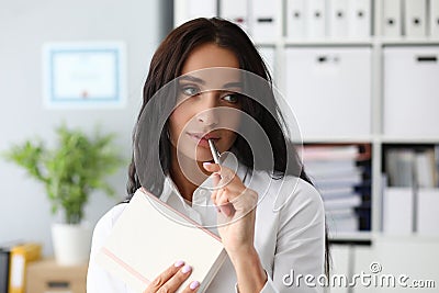 Girl thought touching pen to her mouth, holds note Stock Photo