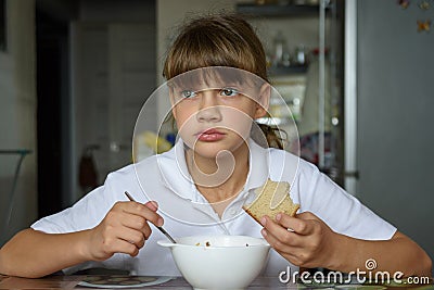 Girl thoughtfully eats soup at the table in the kitchen Stock Photo