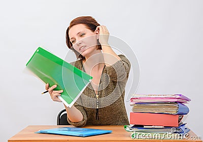 Girl thoughtfully office employee holds documents in a folder and removes hair Stock Photo