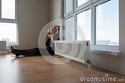 Girl thoughtfully stares into a large window with a glass of wine in her hand Stock Photo