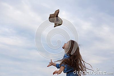 Horizontal photo of a six year old girl who tosses her hat up Stock Photo