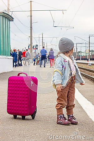 Girl with the travel case on the railway station ready to travel. Stock Photo