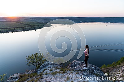 Girl travel in mountains alone. Backpacker walking outdoors, view over river valley landscape in sunlight Stock Photo