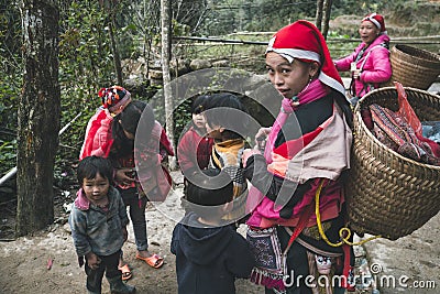 girl from the tribe red dzao, with a large wicker basket behind, surrounded by children Editorial Stock Photo