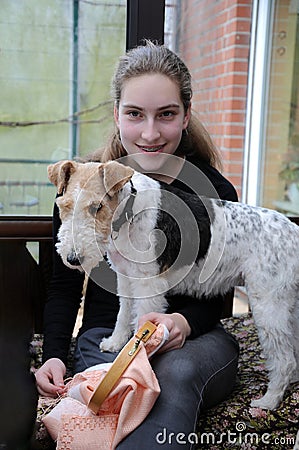 Girl wants to embroider but her dog climbs on her knees Stock Photo