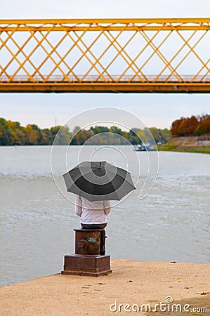 Girl with umbrella sitting on the dock's column Stock Photo