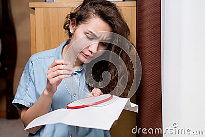 The girl is unhappy, she does not manage to embroider a cross Stock Photo