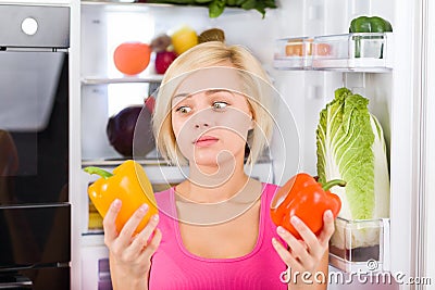 Girl unhappy look red pepper, refrigerator Stock Photo