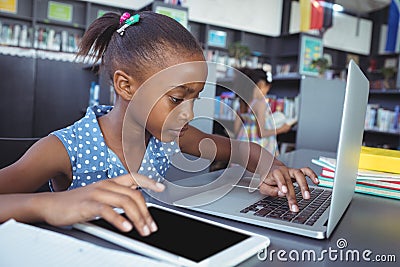 Girl using tablet computer and laptop in library Editorial Stock Photo