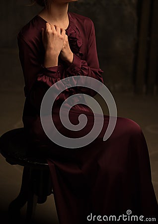 The girl in a vintage dress sits on a chair. modesty. purity. basement. dungeon Stock Photo
