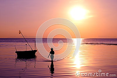 The girl walked on the beach with a fishing boat and sunset. Stock Photo