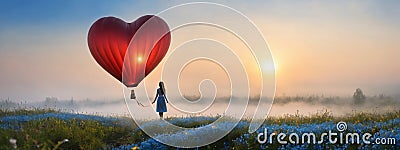 The girl walked in the Don't Forget Me flower field, looking at the heart-shaped balloon ahead Stock Photo