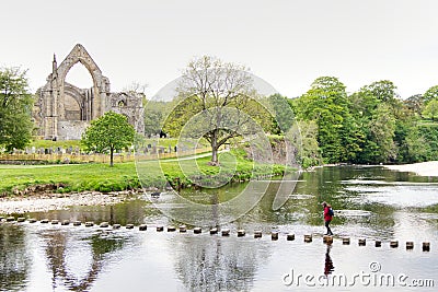 girl walking across stepping stones on a river Editorial Stock Photo