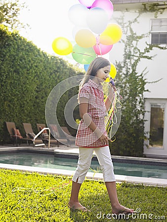 Girl Walking With Balloons By Swimming Pool Stock Photo