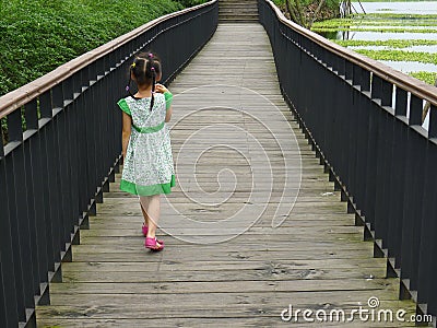 Girl walking on the wooden footbridge Stock Photo