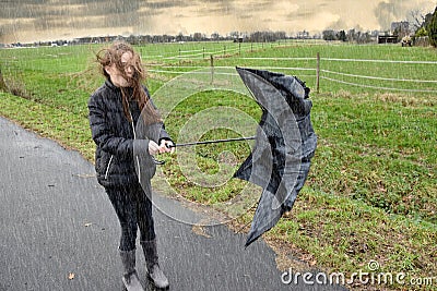 Girl walks through rain and storm, her umbrella is broken Stock Photo