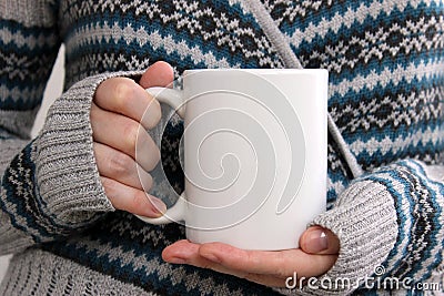 Girl in a warm cardigan is holding white mug in hands. Stock Photo