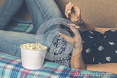 Girl watching tv with popcorn at home in the living room. The concept of laziness Stock Photo