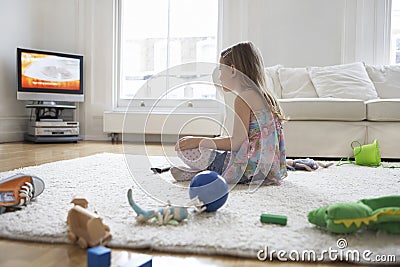 Girl Watching TV With Toys On Floor Stock Photo