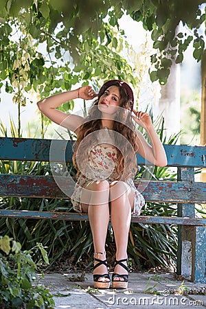 Girl wear short floral dress sitting on a bench Stock Photo