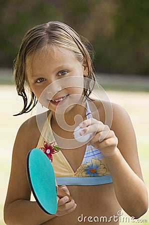 Girl (7-9) wearing bikini holding table tennis paddle and ball portrait. Stock Photo