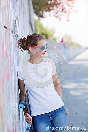 Girl wearing blank white t-shirt, jeans posing against rough street wall Stock Photo