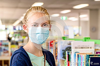 A girl wearing face mask at the llibrary during the COVID-19 pandemic Stock Photo