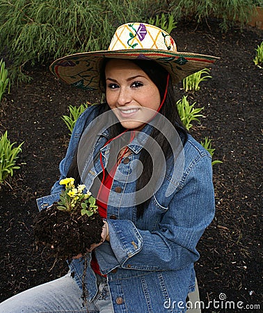 Girl wearing gardening hat planting primrose Stock Photo