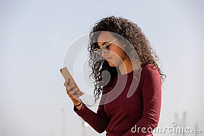 Young And Fashionable Mulatto Girl Using Smartphone Stock Photo