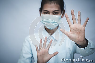 Girl wearing mask for protection from disease and show stop hands gesture for stop corona virus outbreak. Concept against Stock Photo