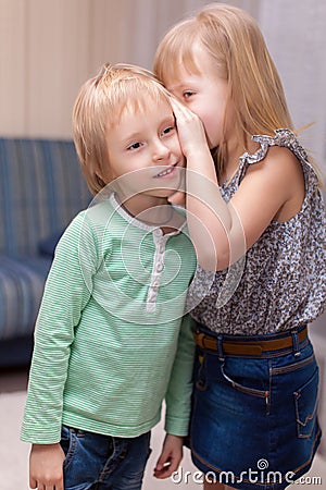 Girl is whispering something to boy Stock Photo