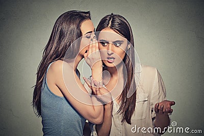 Girl whispering into woman ear telling her shocking secret Stock Photo