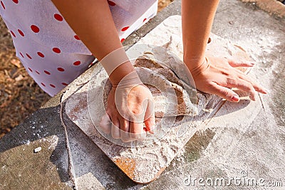 The girl in a white apron prepares the dough on a cutting board Stock Photo