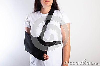 A girl on a white background with a black supporting medical bandage after a dislocation of the shoulder joint and a Stock Photo
