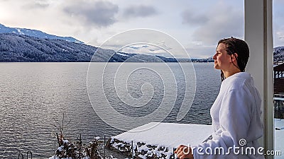 Austria - A girl in a white bathrobe standing on the balcony in winter Stock Photo