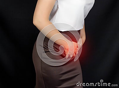 A girl in a white blouse holds onto the groin of the lower abdomen, her stomach hurts, monthlies Stock Photo