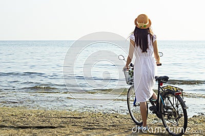 Girl with a bicycle on the seashore, back view Stock Photo