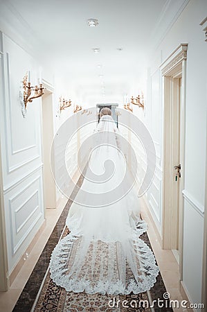 A girl in a white dress walking along a white corridor. Beautiful fashion girl walking along the corridor in a dress. Dress from Stock Photo